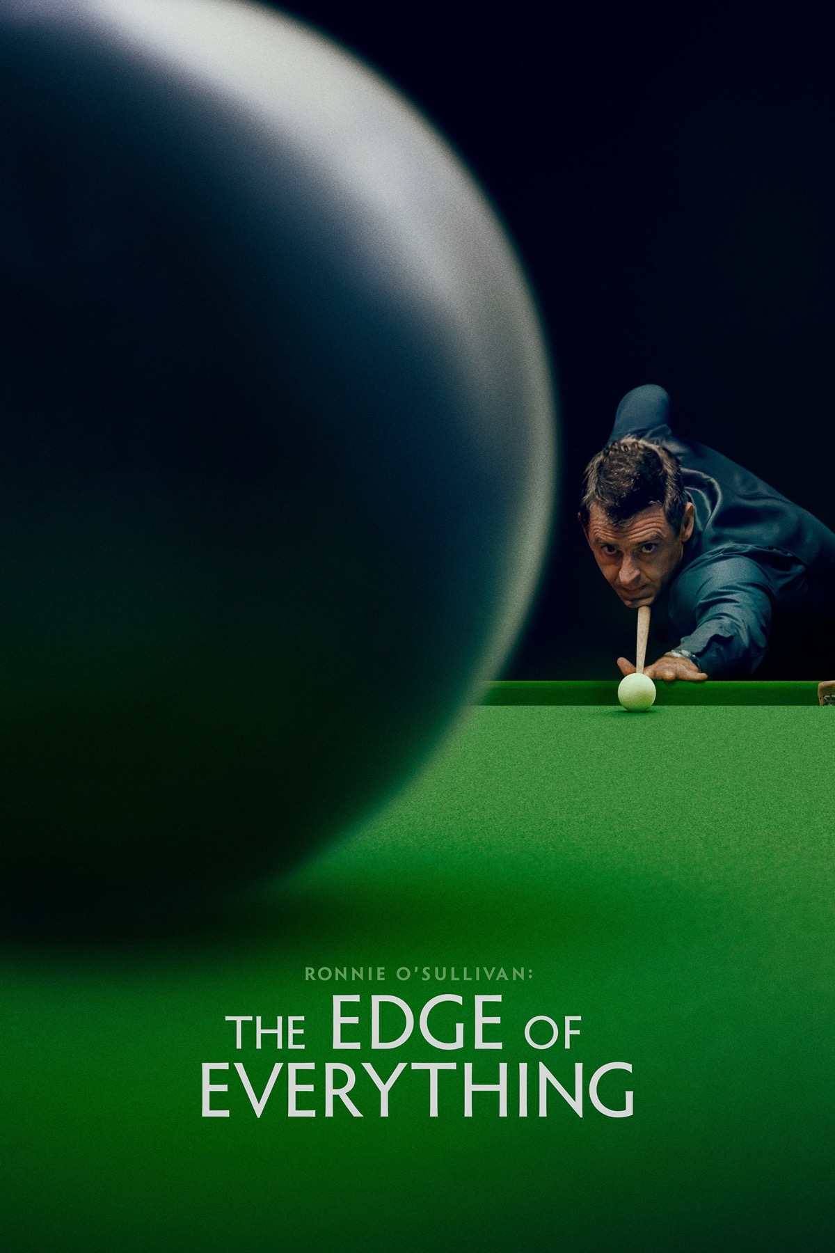 Photo of Ronnie O’sullivan about to take a shot on a snooker table, the camera is just behind and to the side of the black ball he’s aiming at