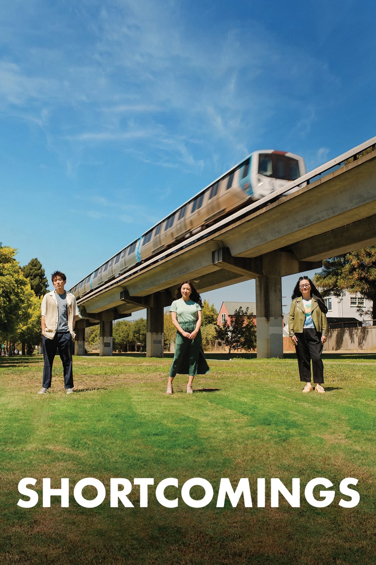 Justin H. Min, Ally Maki & Sherry Cola stood in the middle distance looking at the camera. A monorail goes past behind them.
