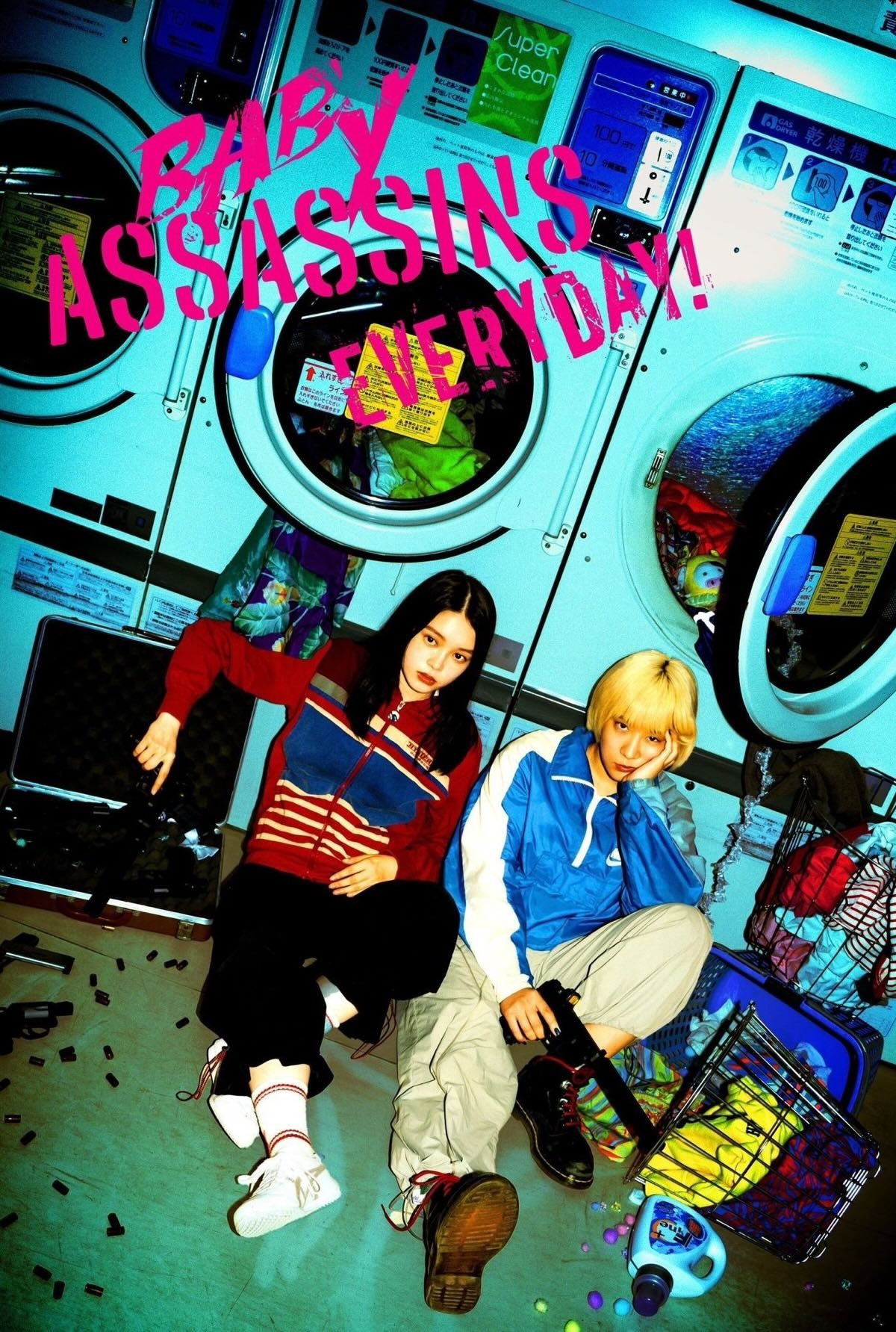 Two young, bored looking Japanese teenagers slouched on the floor of a laundromat. They're both wearing brightly coloured tracksuits and holding guns. There's bullet casings, detergent bottles and clothes spread all over the floor.
