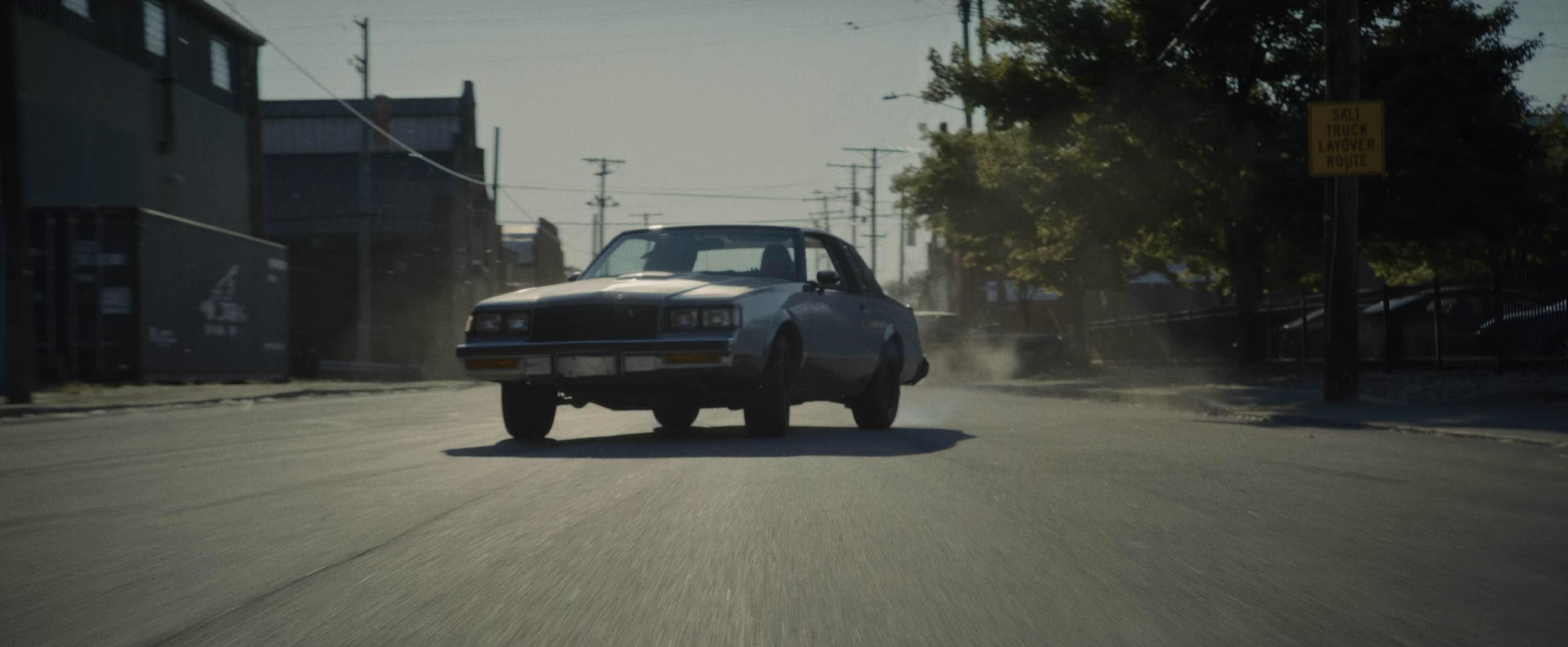 a boxy muscle car, driving towards the camera, coming out of a power slide.