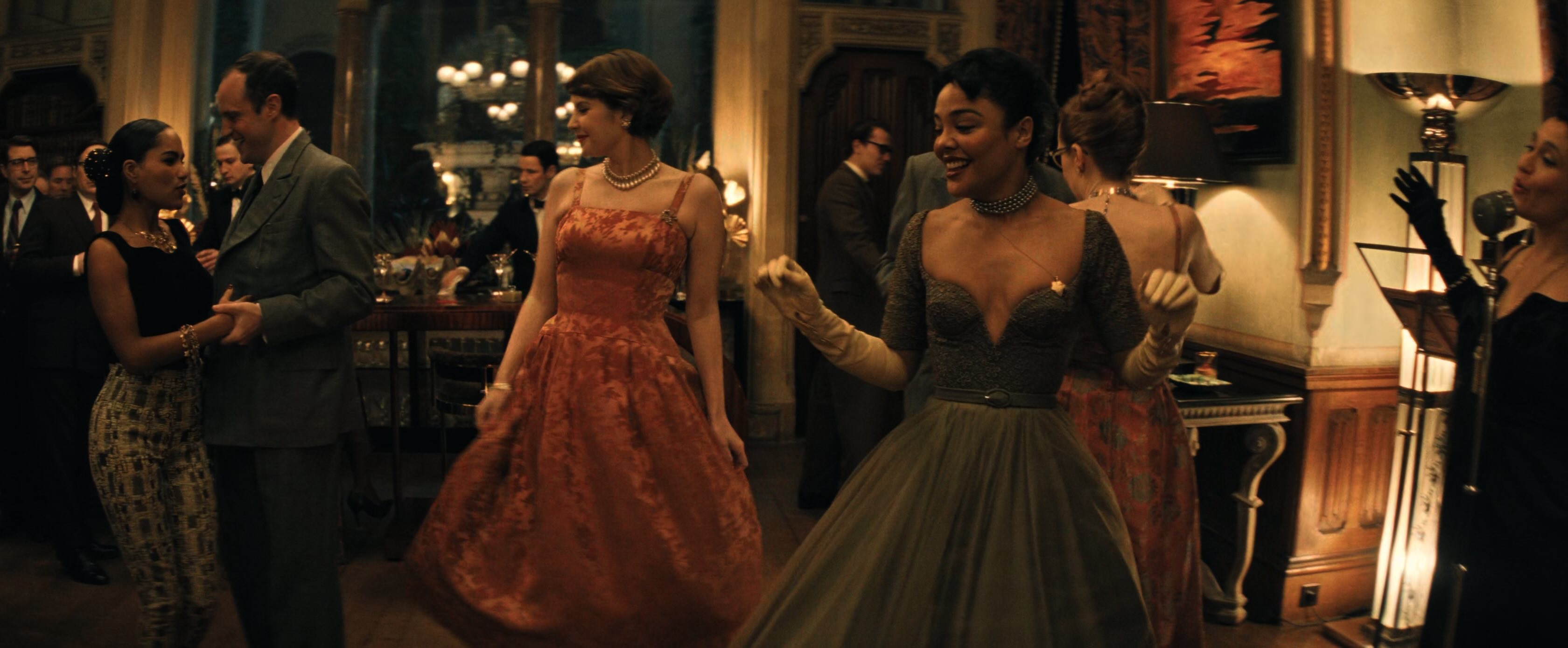 A still from a 1950's dance scene. To the right, a jazz singer, in the centre several women dressed elegantly, dancing.