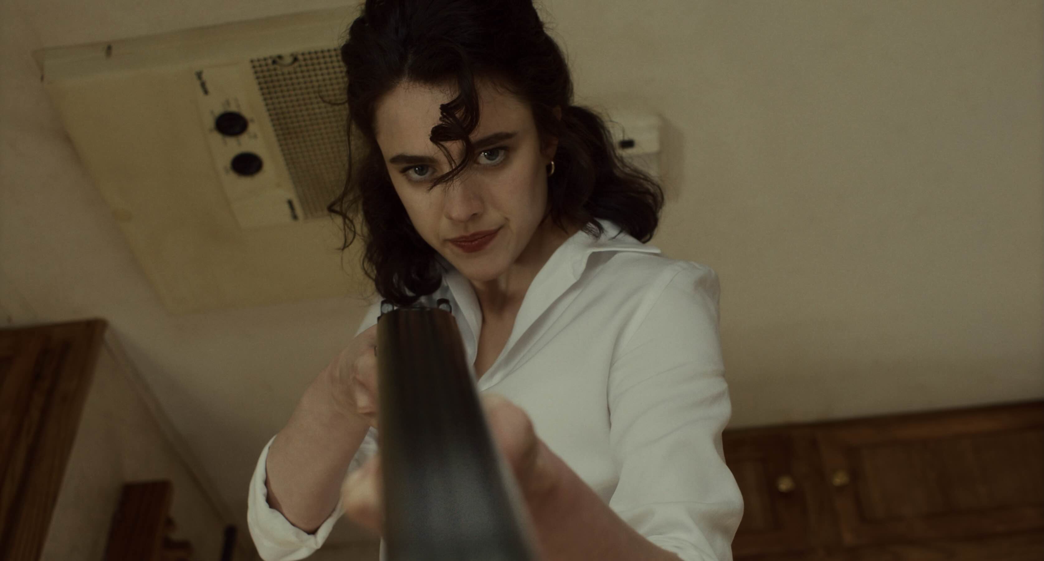 a brunette pointing a double barrelled shotgun right at the camera
