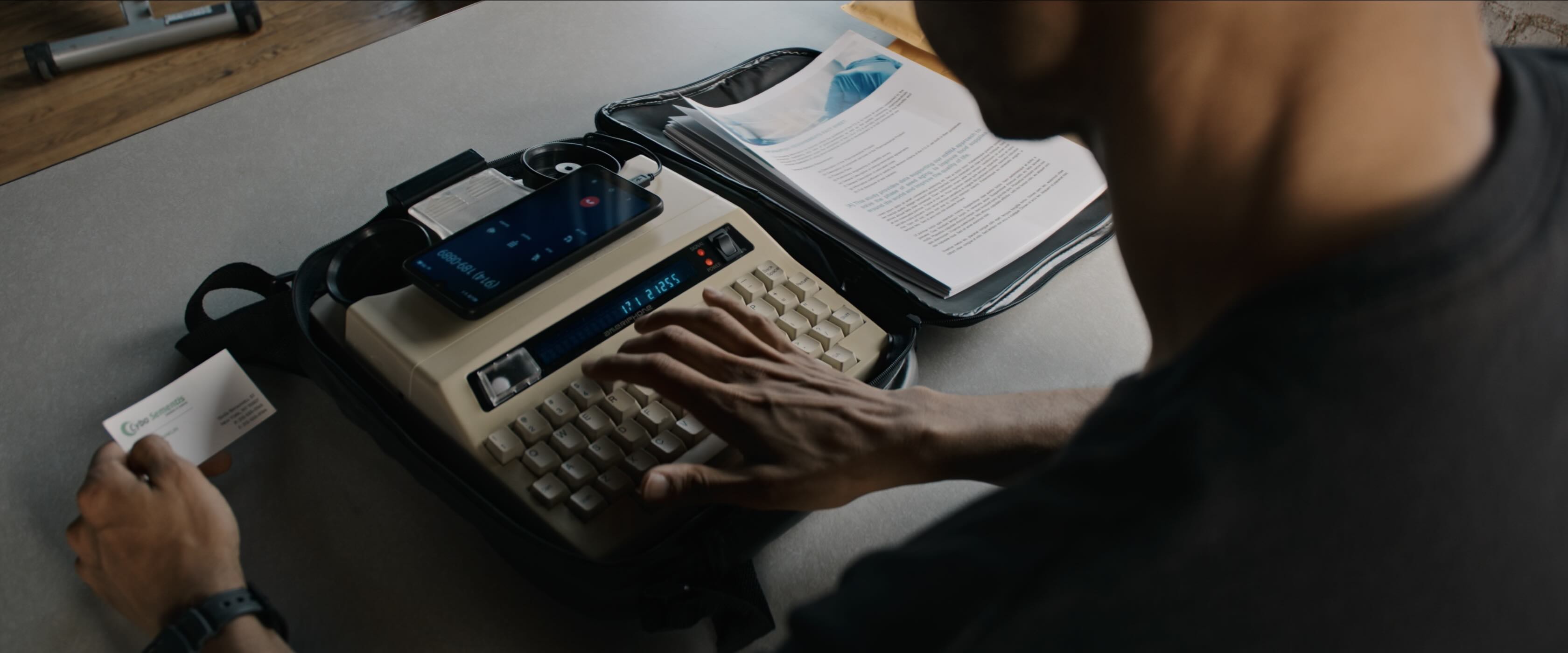 A close up of a relay typing computer, with an old fashioned mechanical keyboard, green VFD text display and big chunky circles to place an old-style handset on to.