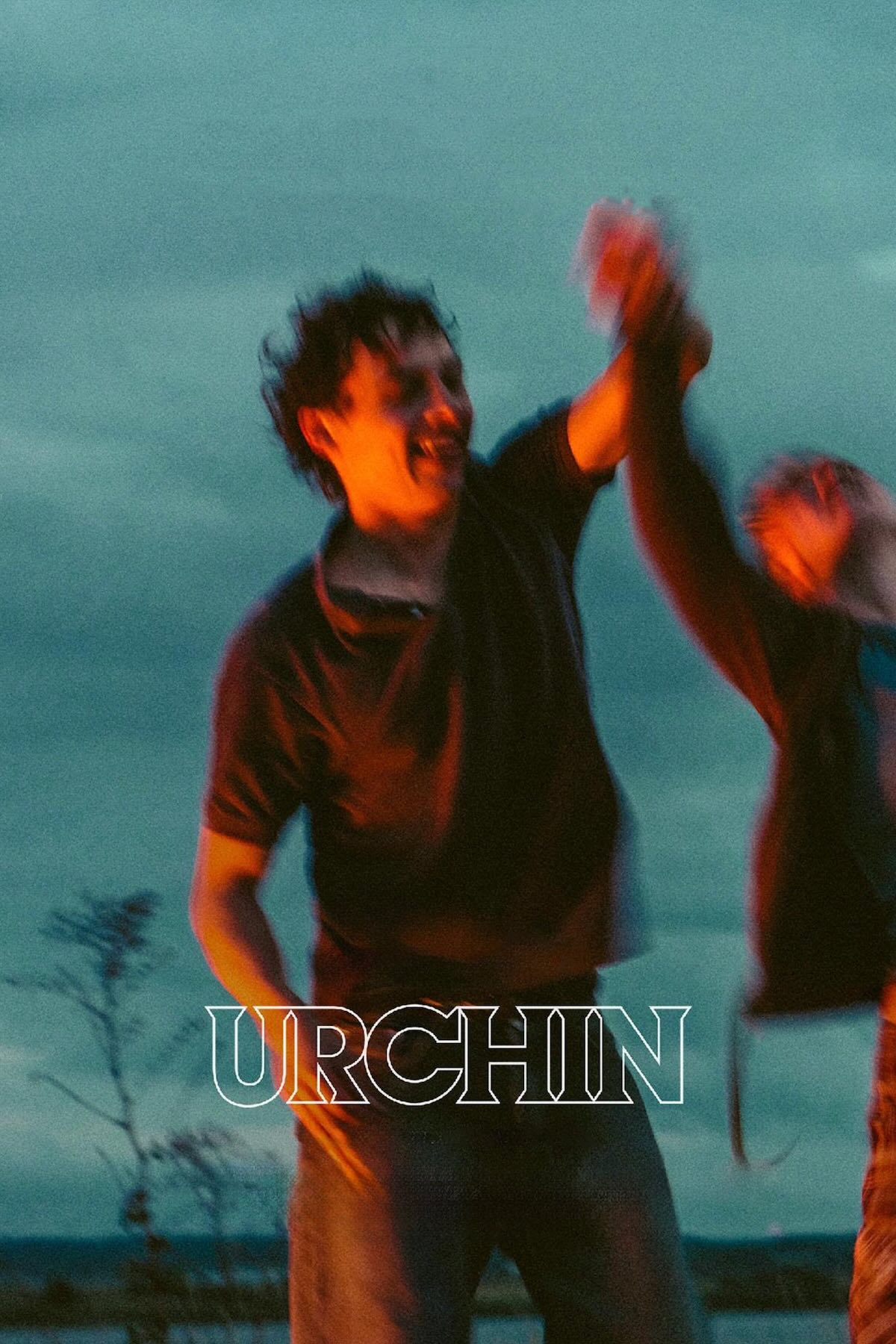 Poster for the film Urchin. A blurred photo of a man dancing at dusk around a fire.